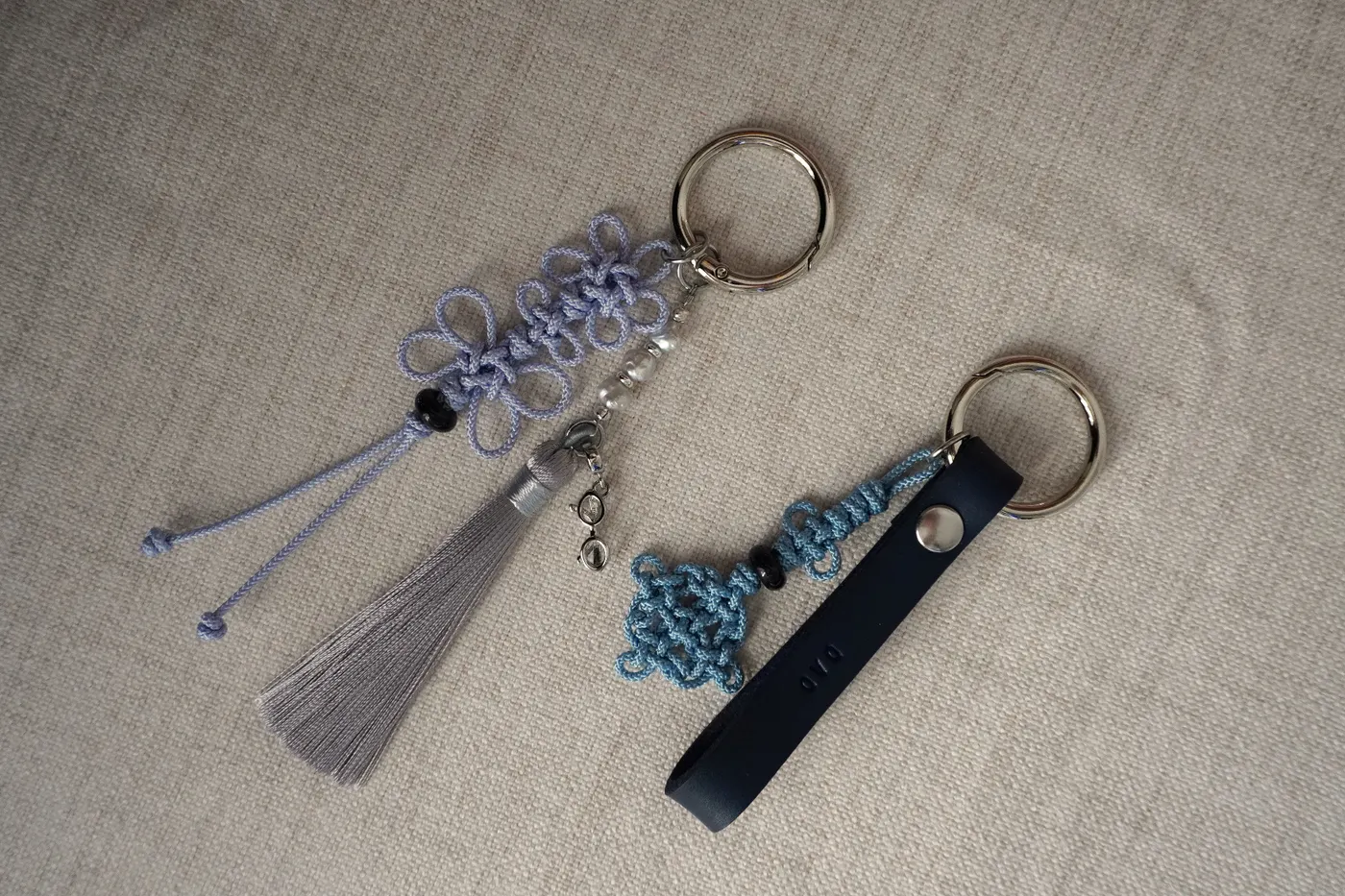 Pink commissioned maedeup butterfly knot keychain with a gold star charm, pale pink tassel, clover detail, and letter beads on linen.