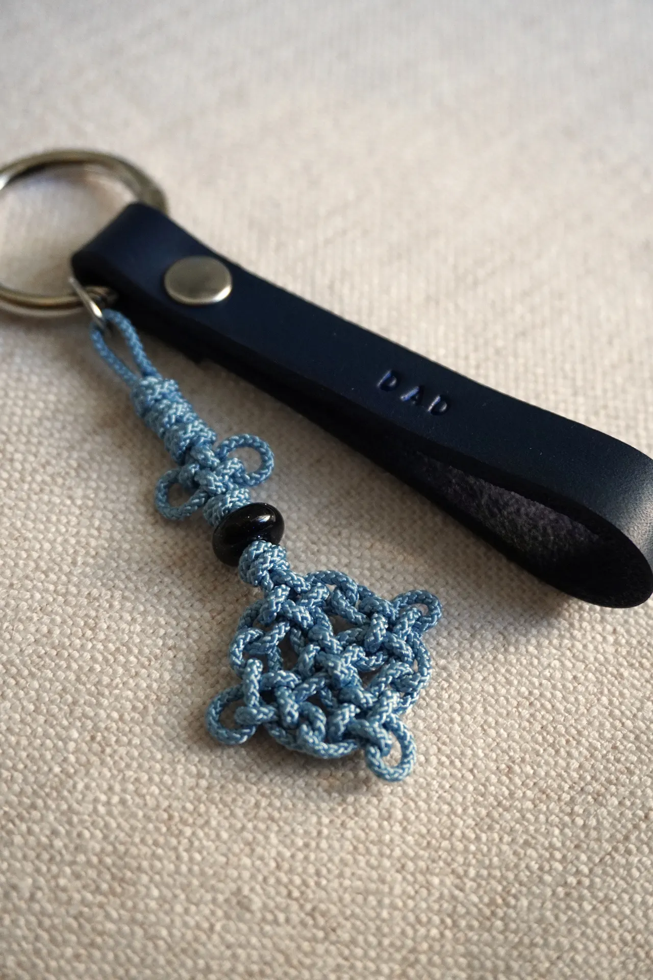 Purple commissioned maedeup tassel keychain with a floral knot, sparkling butterfly charm, and gold ring placed over a children's book illustration.