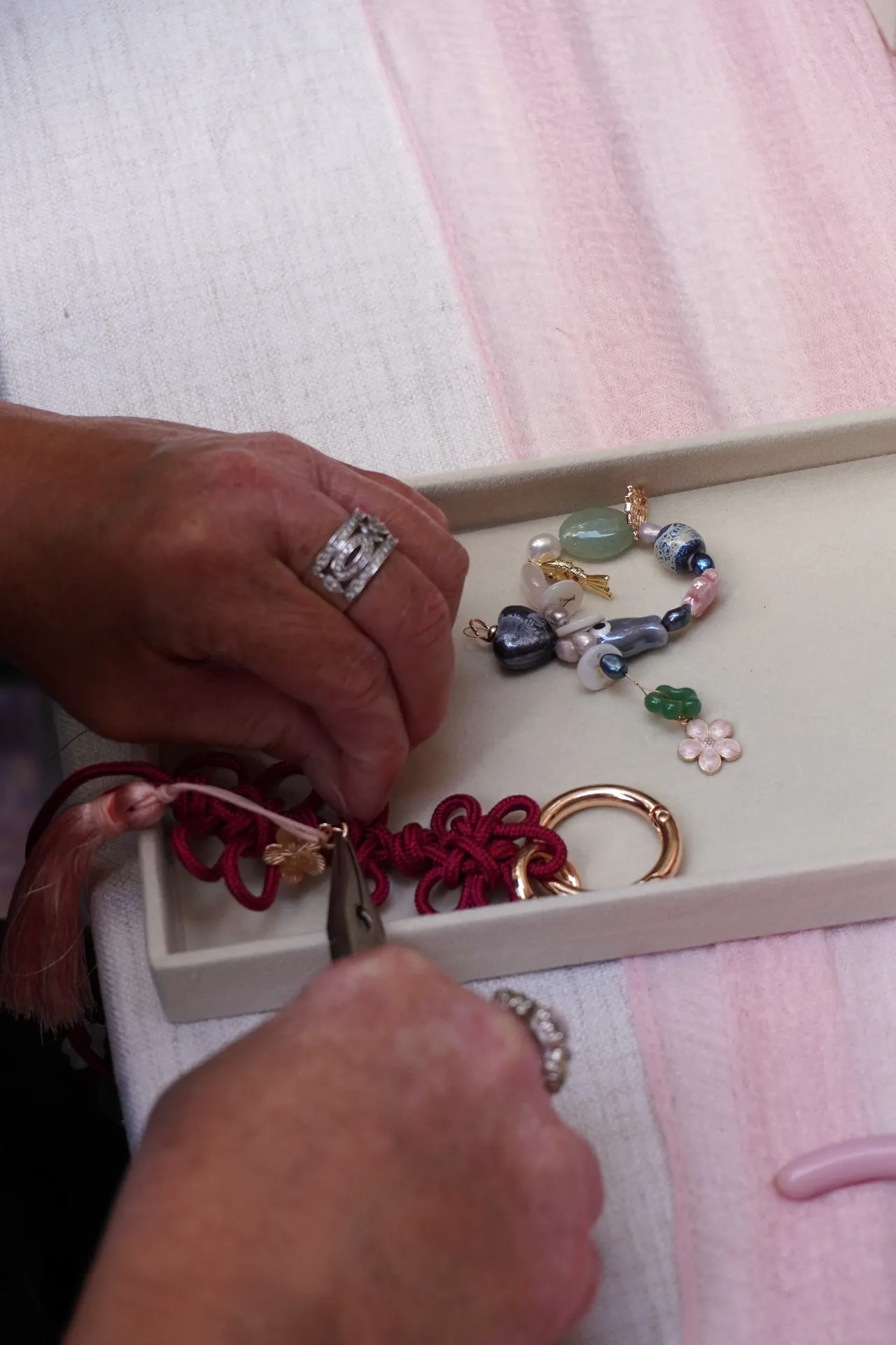 Close-up of beads and tassels being added to a handcrafted maedeup knot during a workshop.