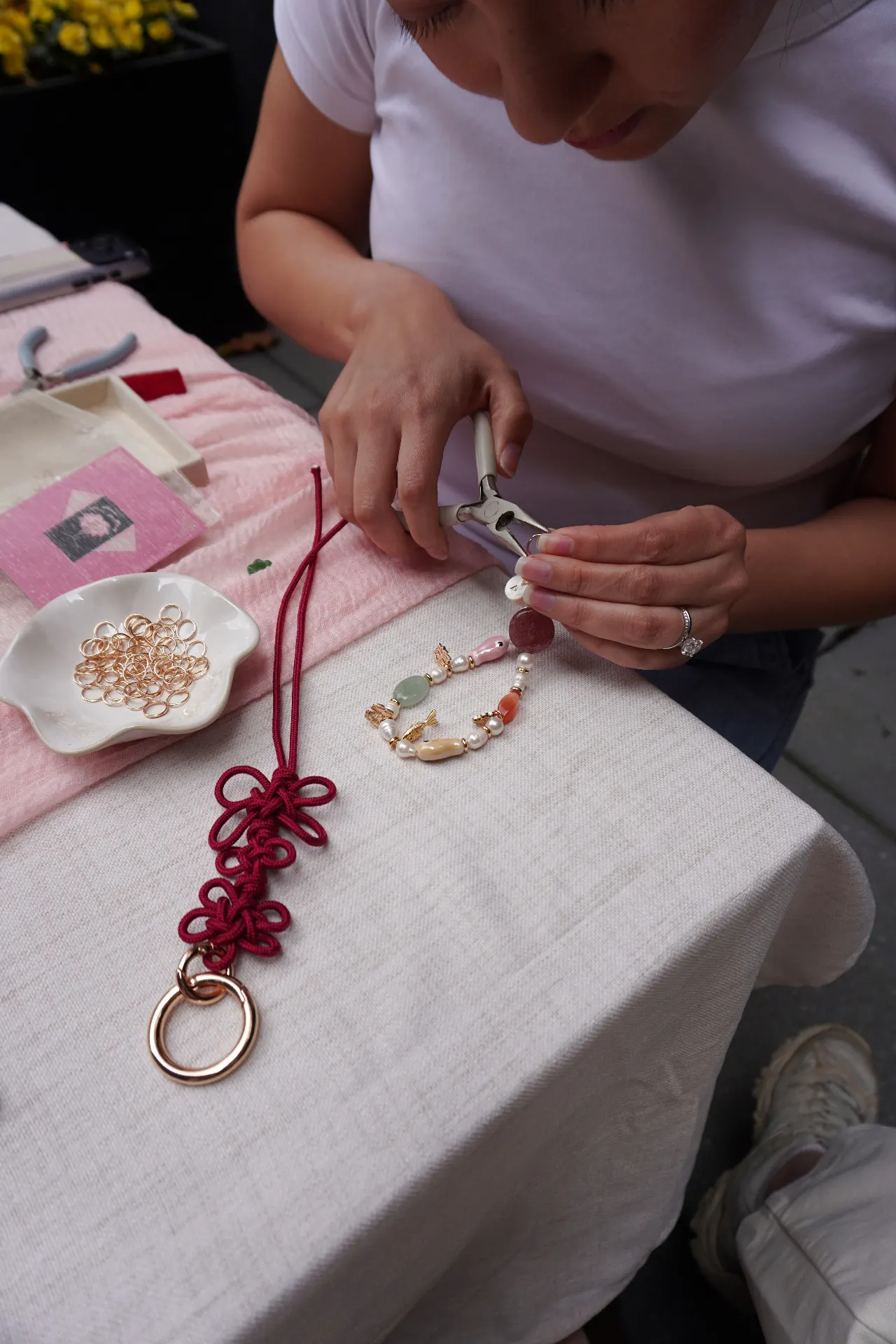 Participant assembling a norigae-inspired bag charm at a corporate Korean knotting workshop.